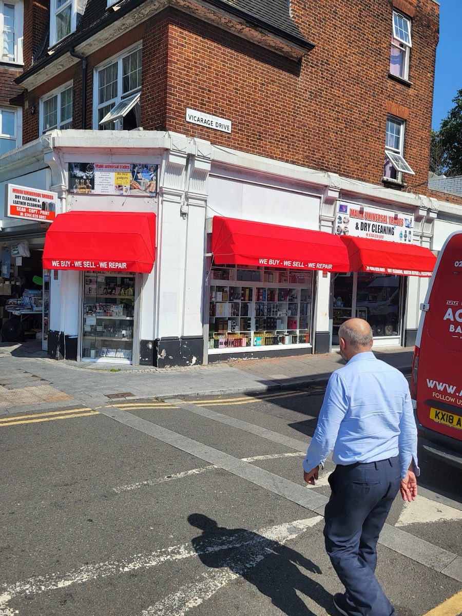 Malik Universal Trades shopfront on the corner of Ripple Road and Vicarage Drive, Barking, with red awnings reading 'we buy, we sell, we repair'